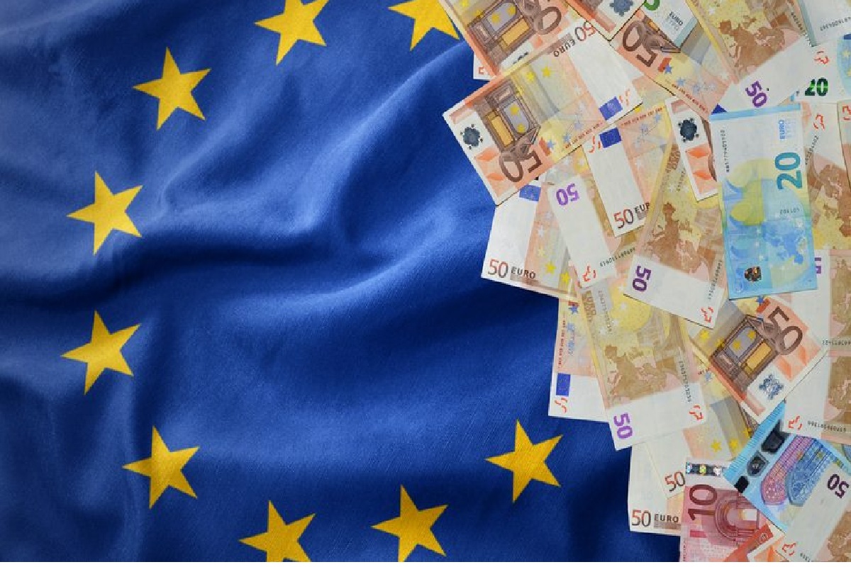 Flaga unijna po lewej i banknoty euro po prawej