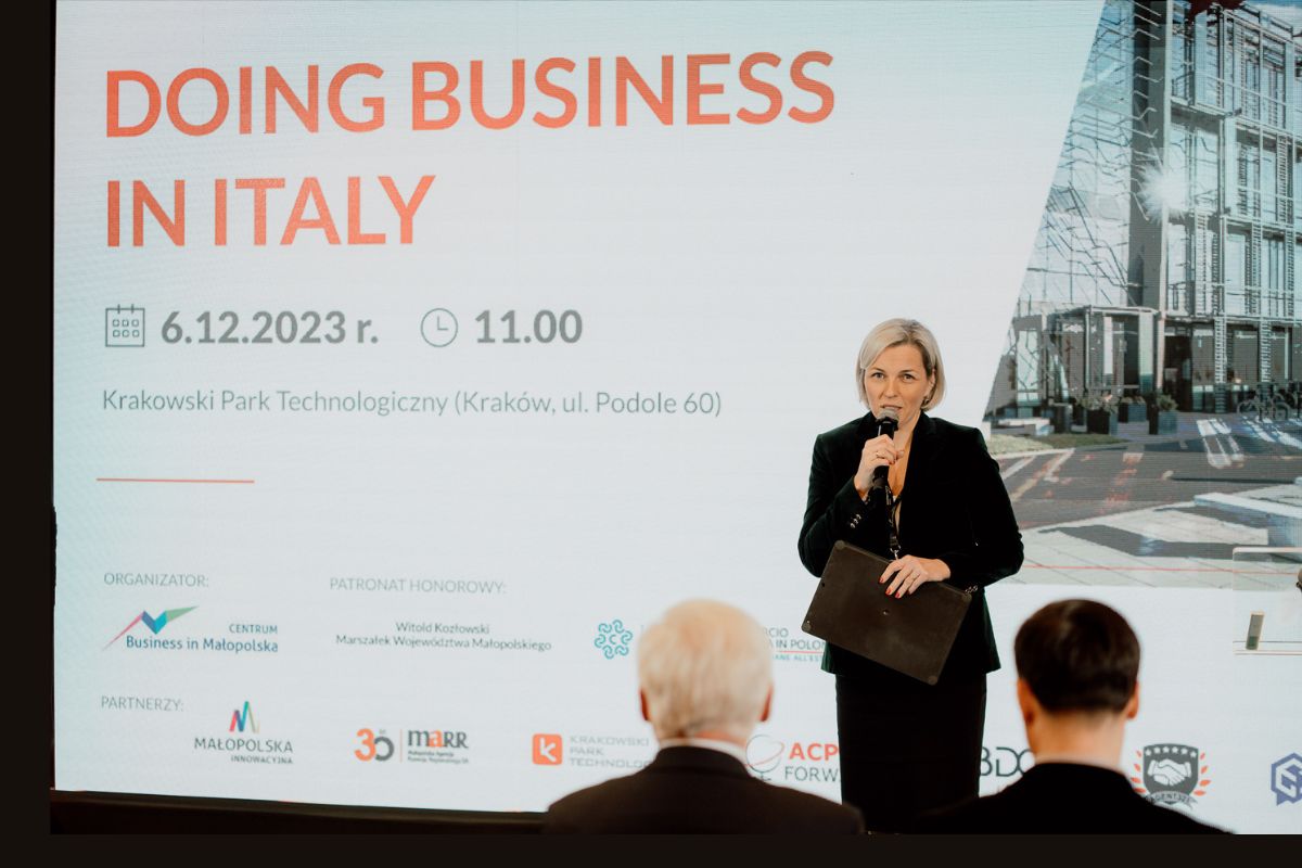 Moderatorka otwierająca konferencję na tle ekranu z napisem Doing business in Italy