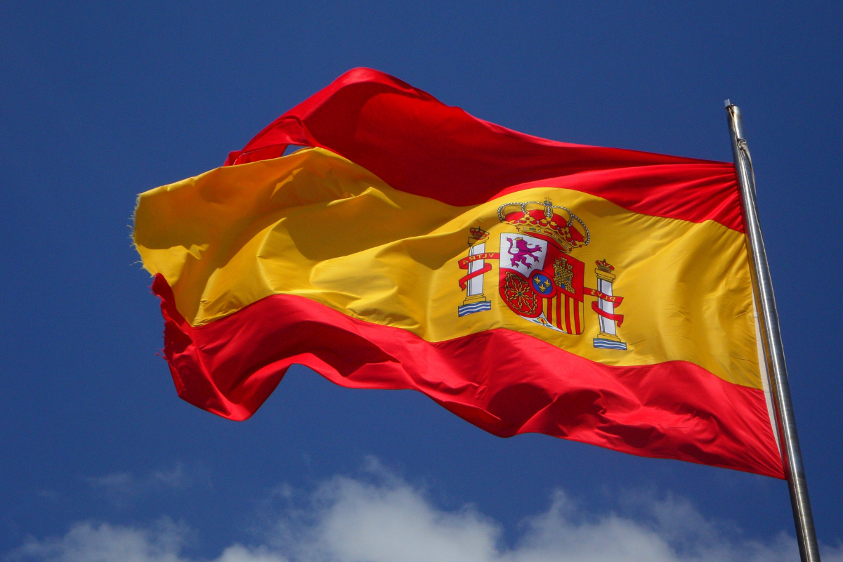 Flaga Hiszpanii powiewająca na tle niebieskiego nieba