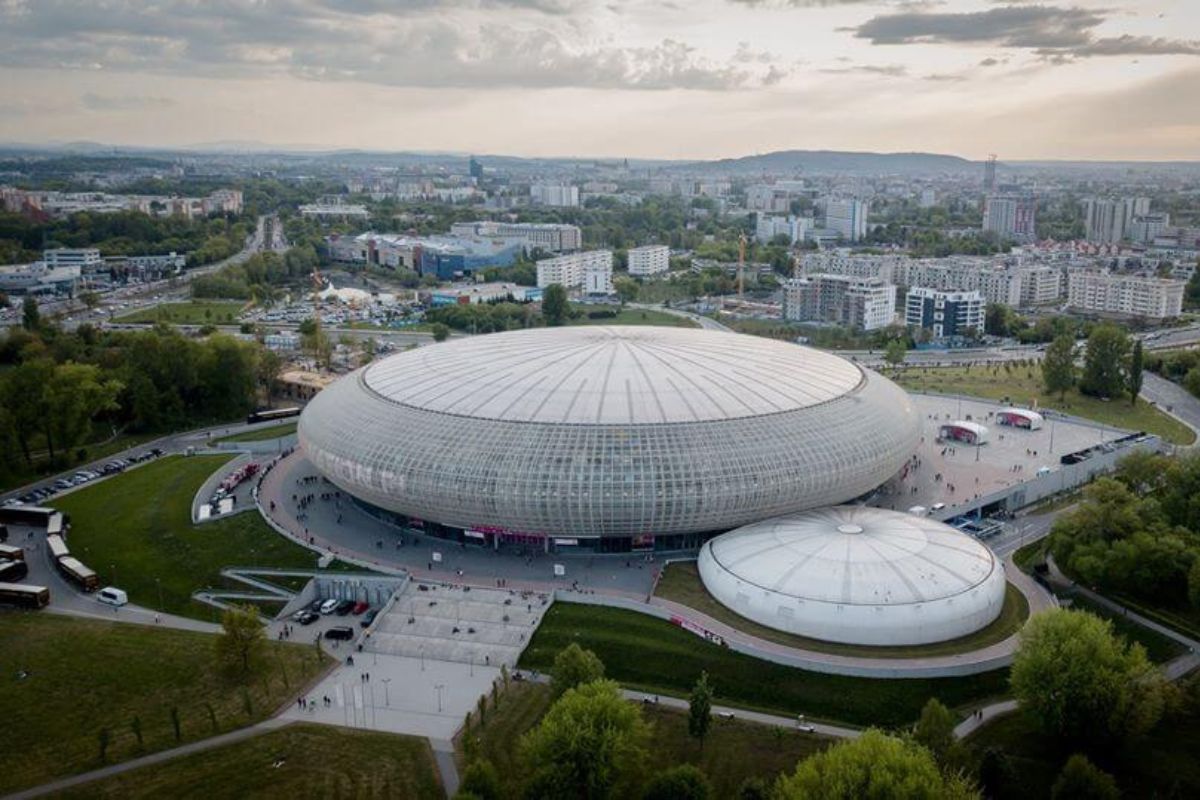 Widok z góry na bryłę areny Tauron, w tle osiedle bloków