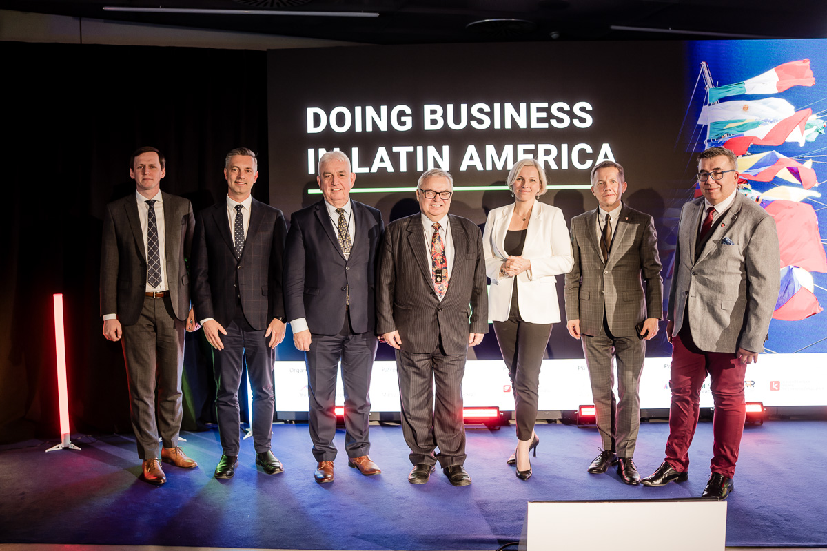 Prelegenci stojący na tle monitora